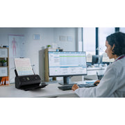 Doctor working at a desk with a Canon Imageformula DR-C350 document scanner in a medical office setting.